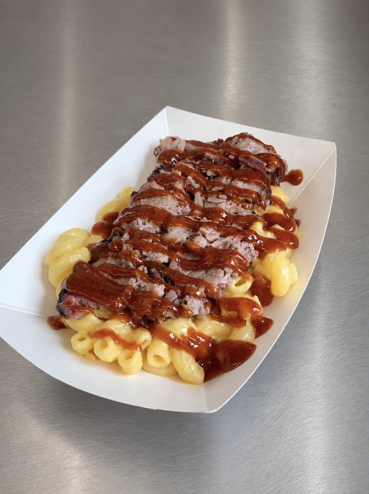 Smoked brisket sliced over four-cheese mac with BBQ sauce